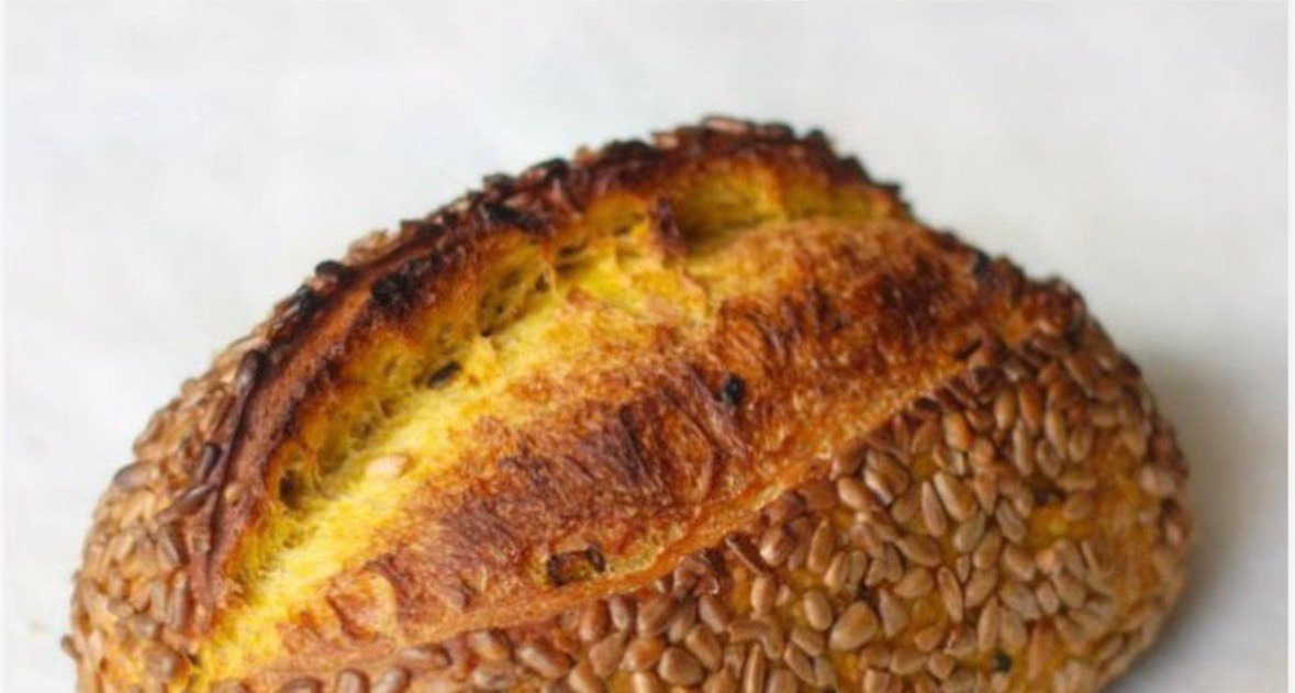 Pão artesanal de abóbora Kabocha com sementes de girassol sobre tábua rústica