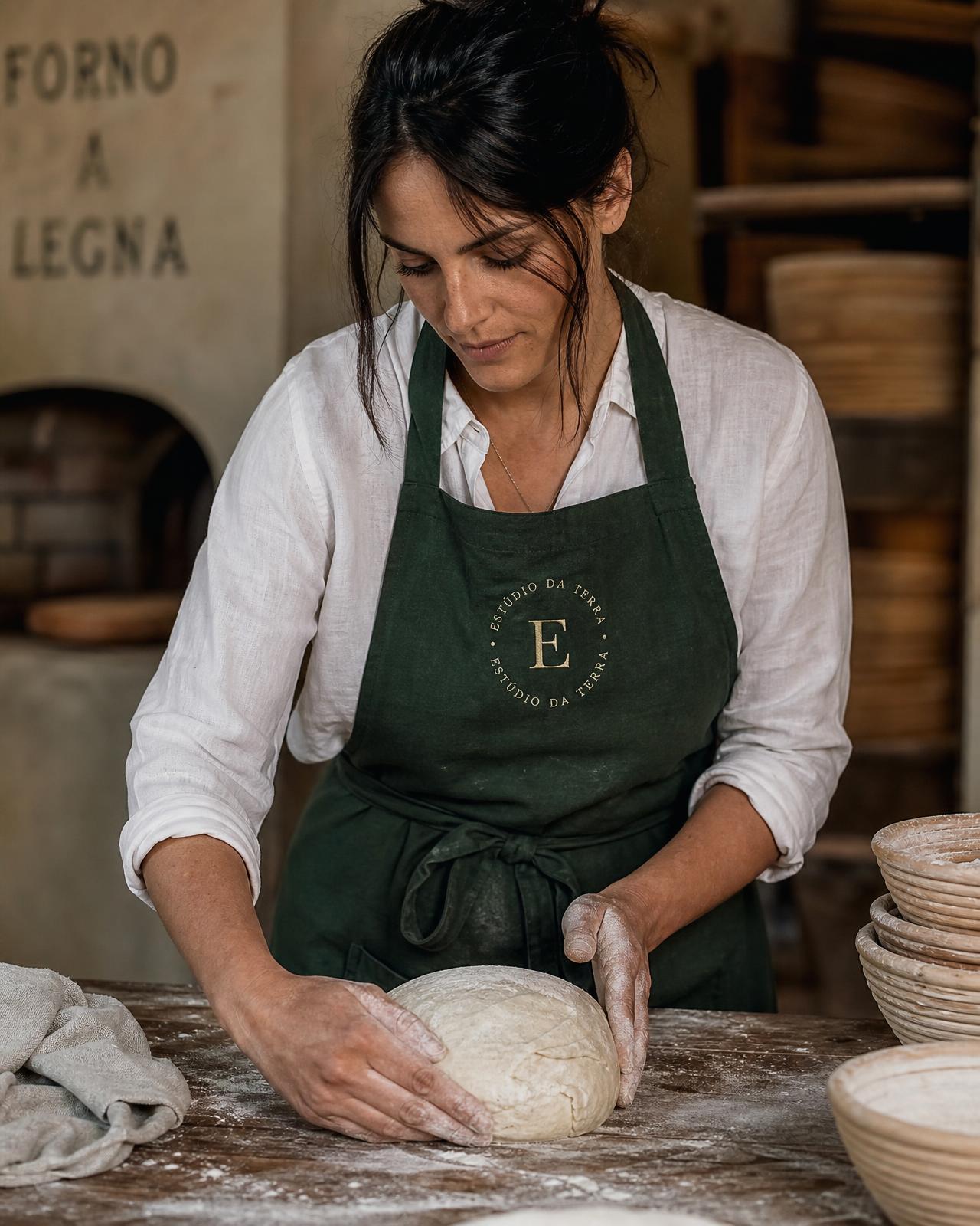 Padeira do Estúdio da Terra, com avental verde e o selo da marca, modelando massa de fermentação natural